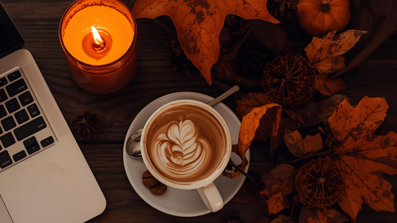 Autumn desk with laptop, candle, and pumpkin decor representing financial clarity of the Mojo Number during spooky season.